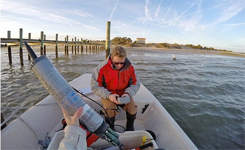 Photo of a person in a boat looking at a data logger