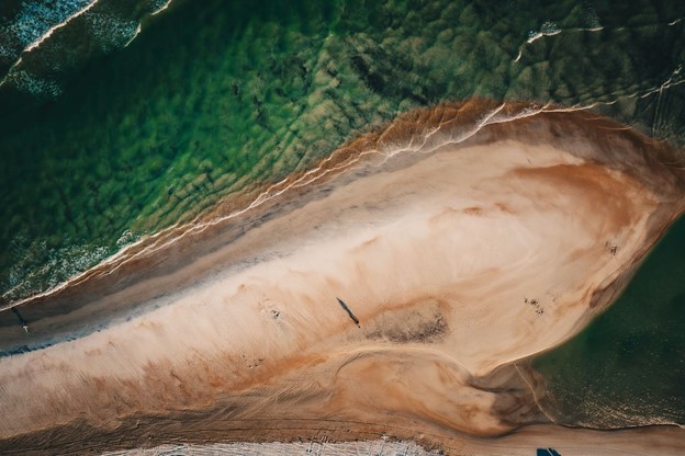 Aerial view of a person walking on the beach, near the ocean.