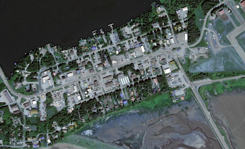 Aerial view of roads with buildings along it. A marsh on one side and water on the other.