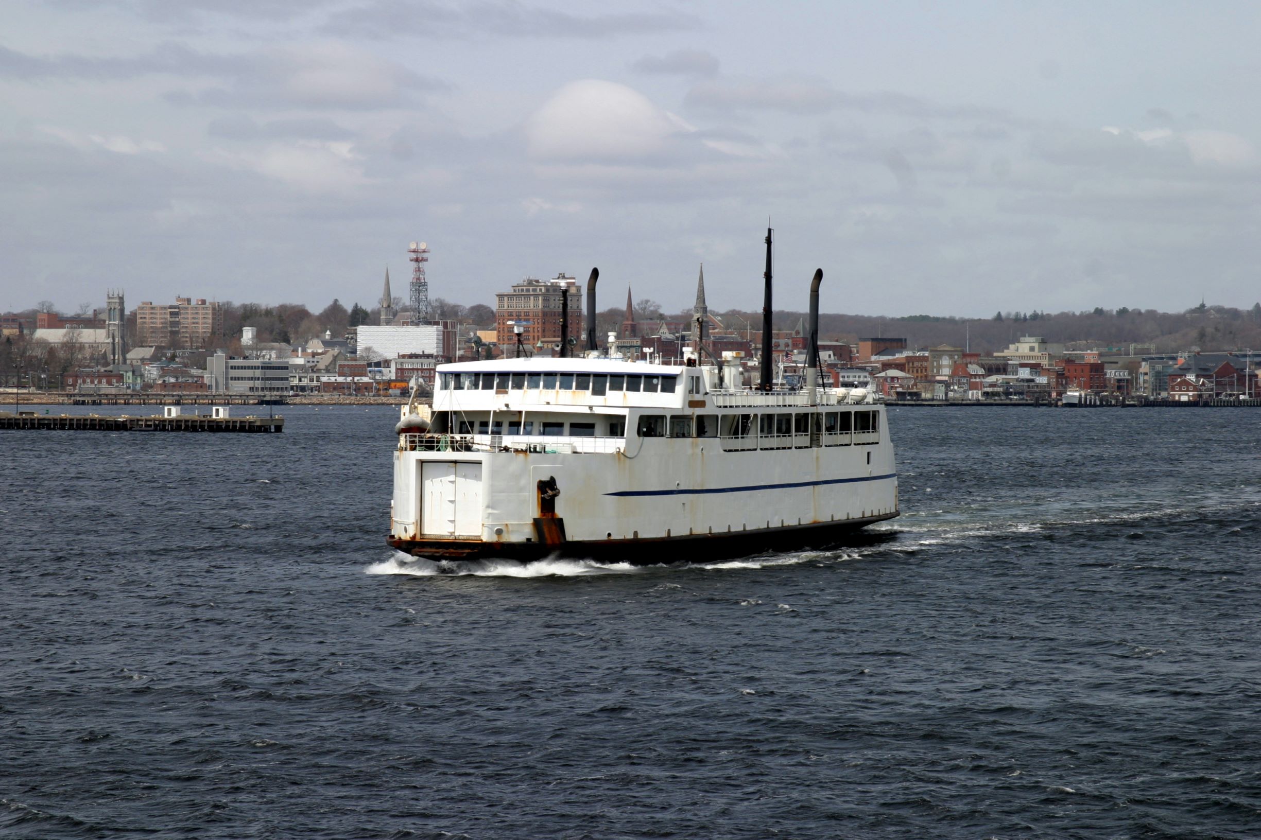 A ferry is traveling an urban waterway.