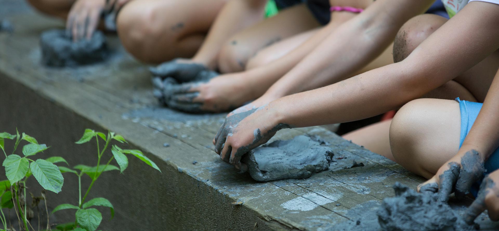 Detail image of hands of children shaping clay from the estuary.