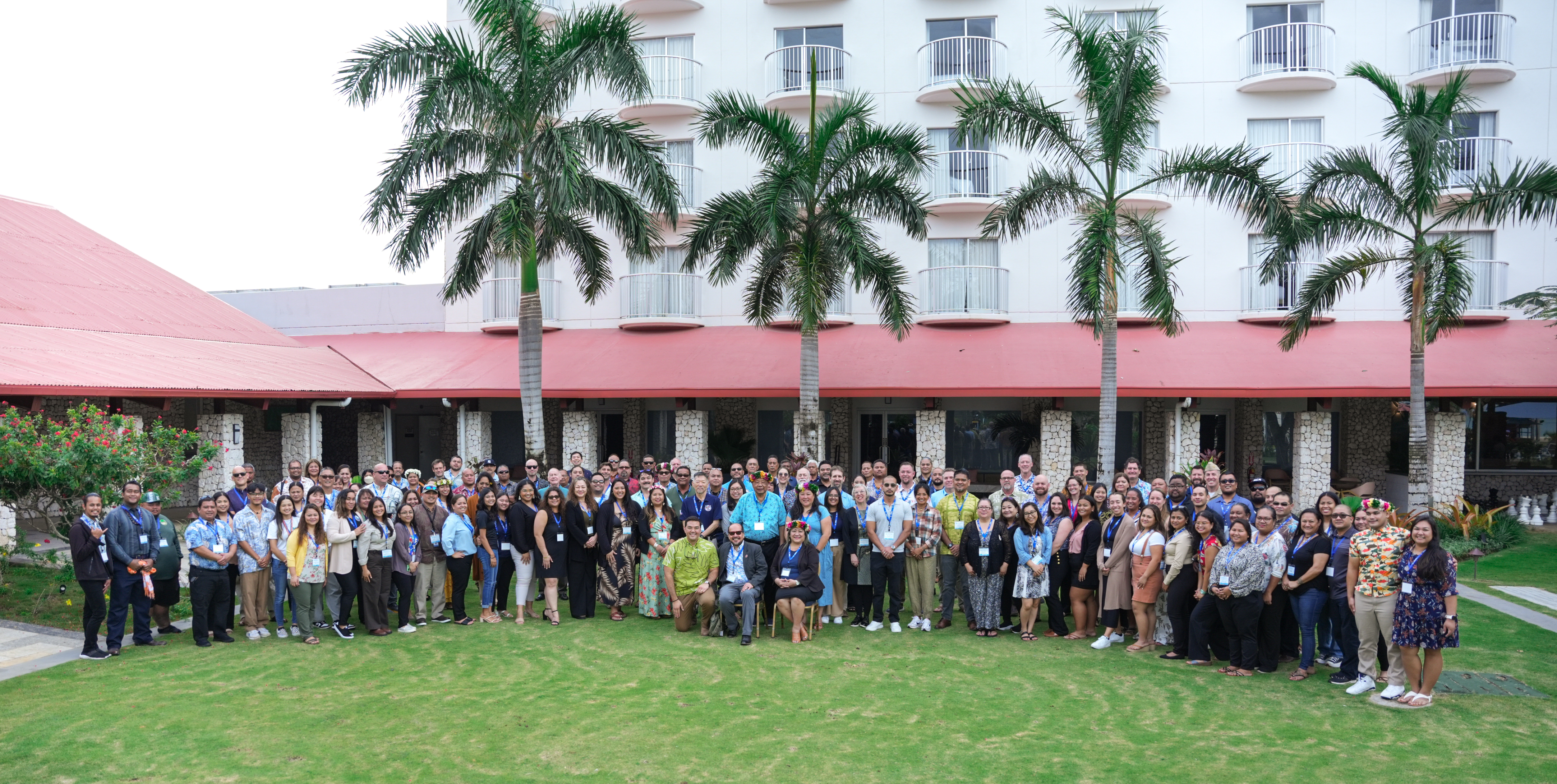 A group of people standing in front of a building with palm trees